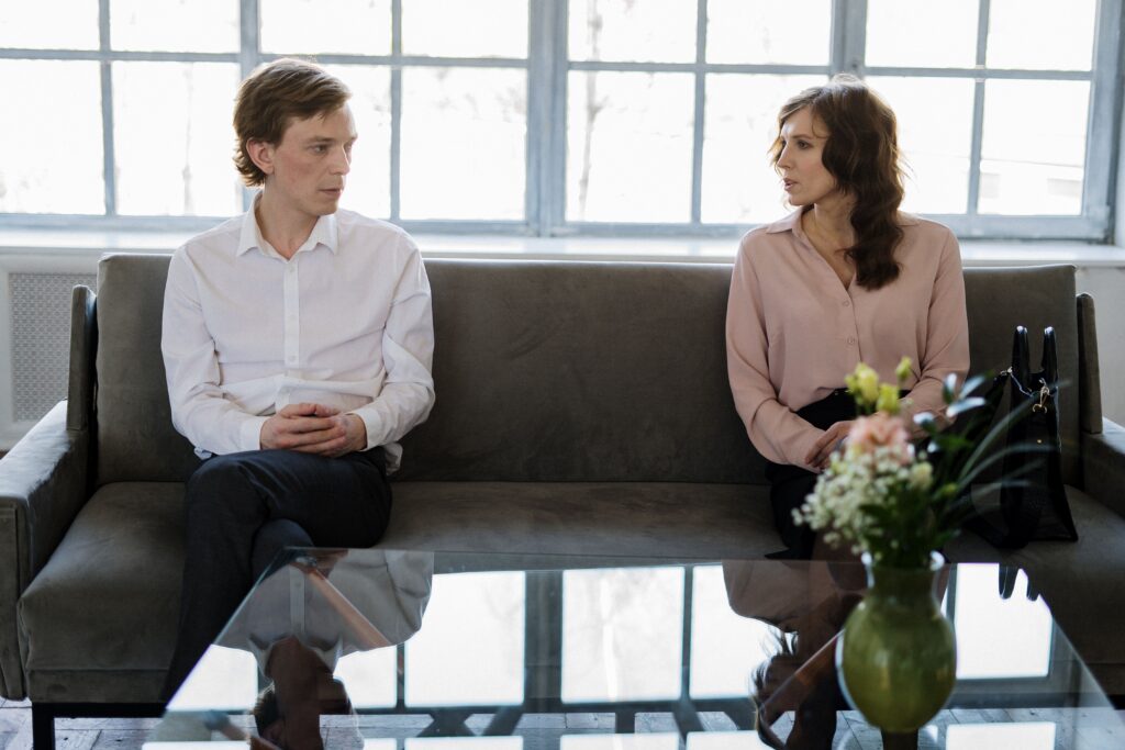 A couple engaged in a therapy session, seated on a couch in a bright modern office.